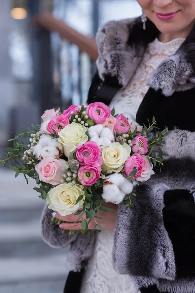 Bride in beautiful winter mittens holds a Winter Wedding bouquet.