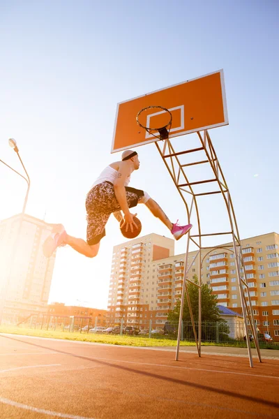 One guy play basketball at district sports ground.