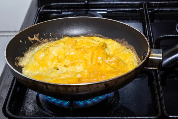 Scrambled eggs cooking in pan on gas flame