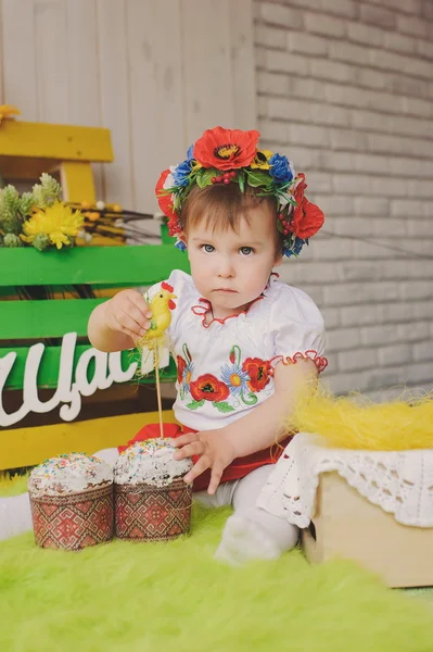 Child in Ukrainian national costume with Easter cake. Text happiness.