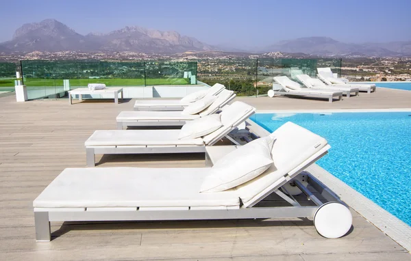 Swimming pool area with white sun beds at the modern resort.