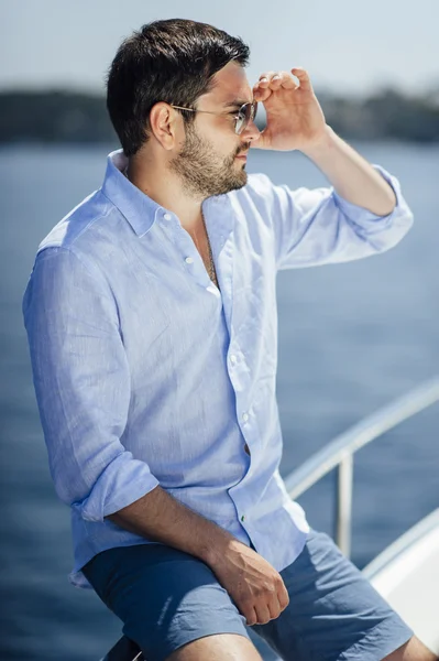 Handsome man on a yacht enjoy bright sun light on vacation