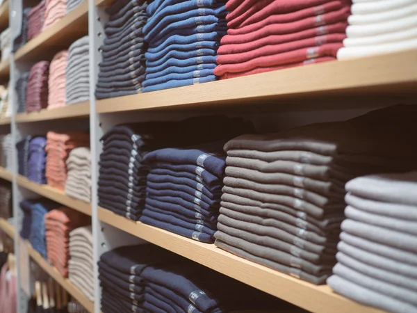 Neatly folded clothes. Rack of clothes with warm. Wooden cabinet