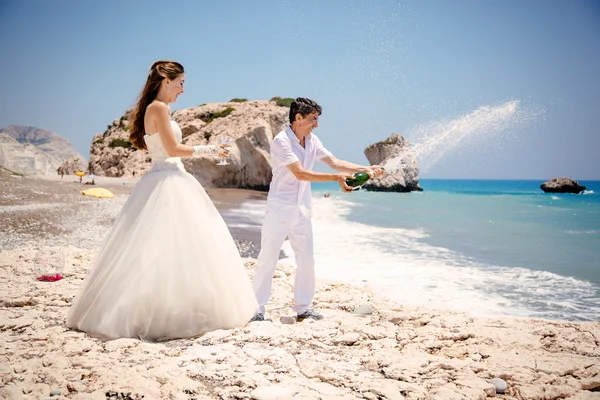 Bride and groom open champagne on the beach Mediterranean Sea