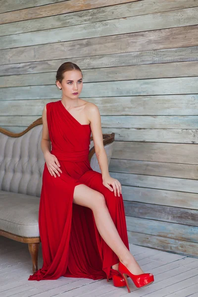 Luxurious woman in a red dress on couch