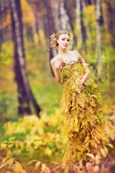 Beautiful woman in dress made with fern leaves. Forest landscape. Eco material concept.Ecological material clothes.  Woman in the forest.