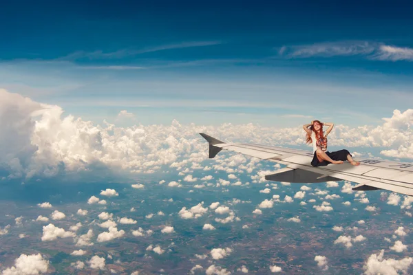 Relaxing young red hair woman on the airplane\'s wings. Free travel concept. Traveling woman. Freedom concept.