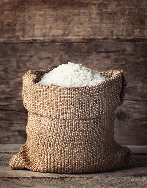 Rice in bag on wooden background