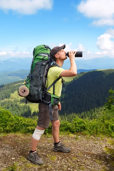 Man in top of mountain hiking drinking water