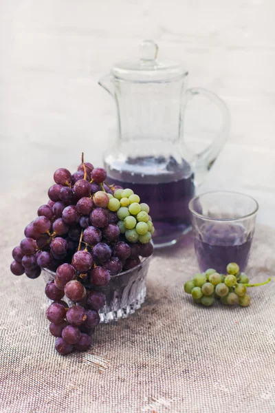 Fresh green and blue grapes on natural textured canvas.A carafe of grape juice