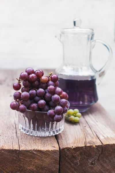 Fresh green  blue grapes and carafe of grape juice  on wooden table