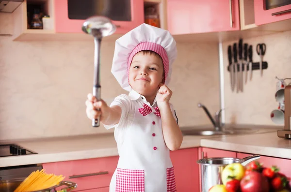 Portrait of little boy in the hat of the chef and an apron. Little cooks chef in the kitchen.Emotional pictures.