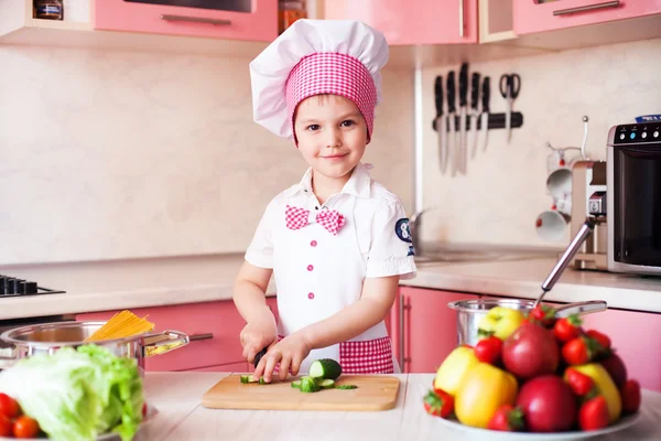 Portrait of little boy in the hat of the chef and an apron. Little chef cooks in the kitchen.Portrait of cute boy helping at kitchen
