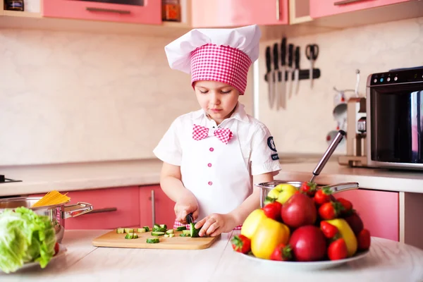 Portrait of little boy in the hat of the chef and an apron. Little cooks chef in the kitchen tasting the dish.