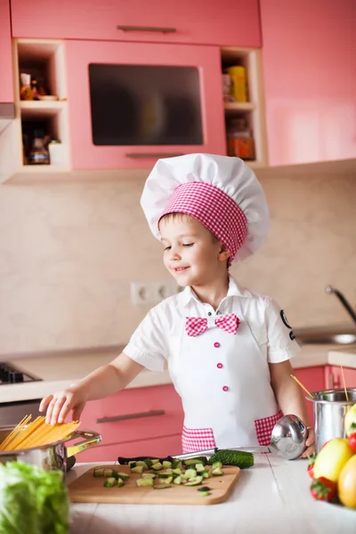 Portrait of little boy in the hat of the chef and an apron. Little cooks chef in the kitchen