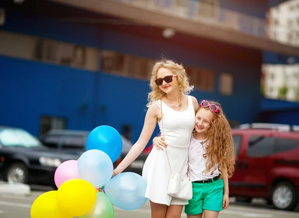 Little child and sister having fun outdoors with lots of colorful balloons, a happy family life