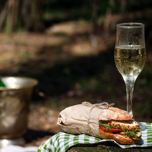 Champagne and sandwich in the woods on a picnic