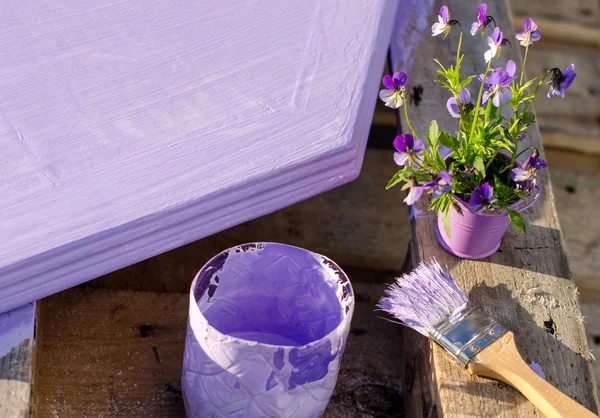 Purple paint in a jar and brush on the background of painted boa