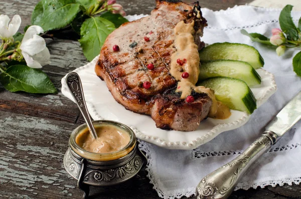 Pork steak, mustard in a jar on the table. Vintage style.