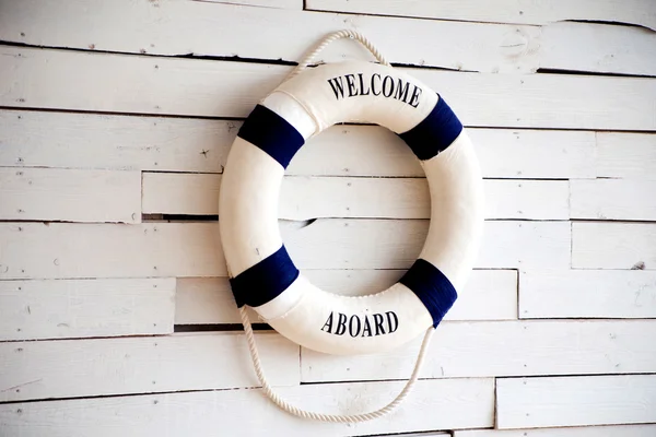 White Life buoy with welcome aboard on white wall
