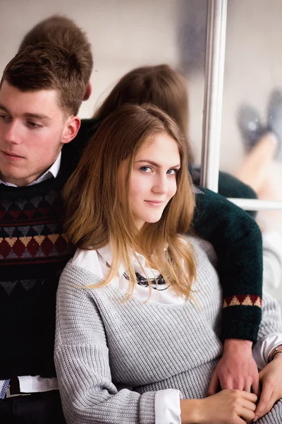 Couple of teenagers sitting against mirror wall