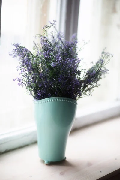 Lavender flowers are in the vase on the window of the house
