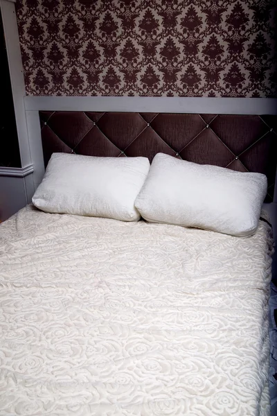 Detail of classic furniture bed with pillows in bedroom.