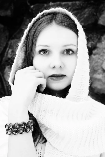 Feminine girl in a white scarf over  a stone wall. Black and whi