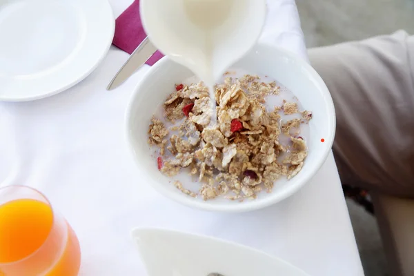 Milk pouring into bowl of cereals