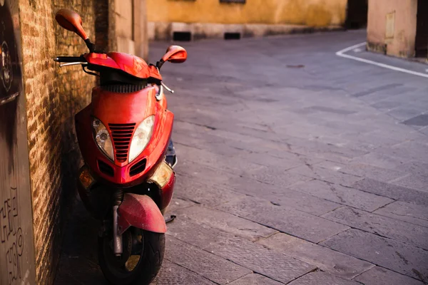 Motor scooter parked in front of a building wall