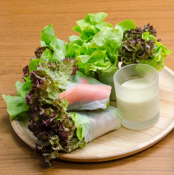 Salad roll vegetables and crab stick with salad dressing in wood