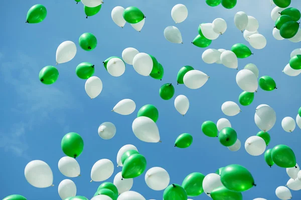 Green and white balloons in the sky