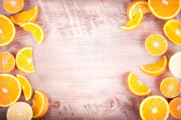 A closeup of a pile of oranges sliced and lemons sliced on wooden background. Eating frame. Free space for text