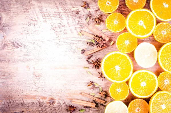 A closeup of a pile of oranges sliced and lemons sliced with spices on wooden background. Eating frame. Free space for text. Christmas