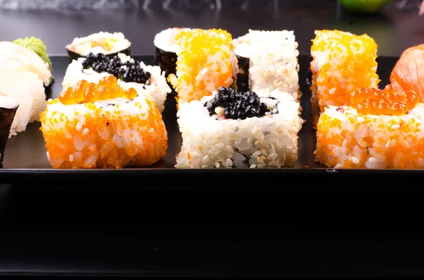 Sushi set served on a plate on black background, close up