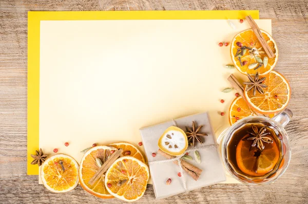 Dried oranges, cinnamon, cloves, cardamom, handmade milk chocolate in rustic packing, mulled wine on yellow and wooden background. Christmas, New Year and winter. Free space for your text.