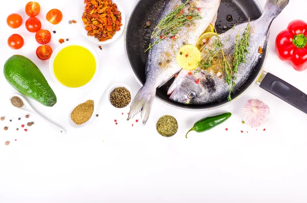 Fresh raw gilthead fishes with lemon, herbs, salt on white background. Healthy food concept. Food frame. Free space for your text.