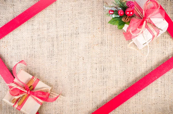 Two Christmas gifts with red tapes over sackcloth texture background, free space for your text.