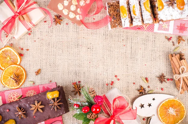 Chocolate spices cake, star anise and dried fruits, packed gifts with red tapes on sackcloth, canvas. Sweet frame. Free space for your text.