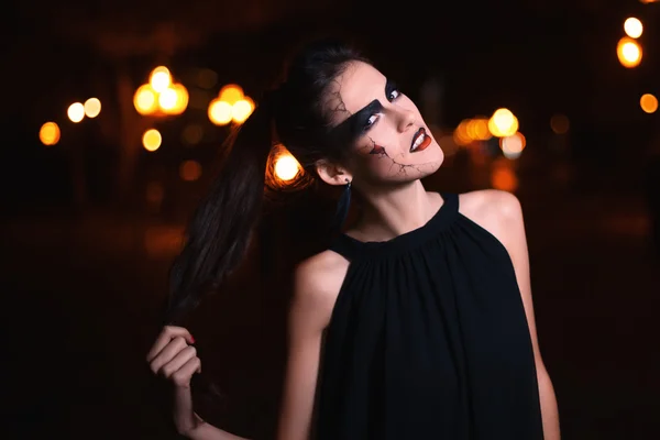 Beautiful woman with Halloween makeup posing on the street . Model looking at camera. Close up. Night city background. Toned