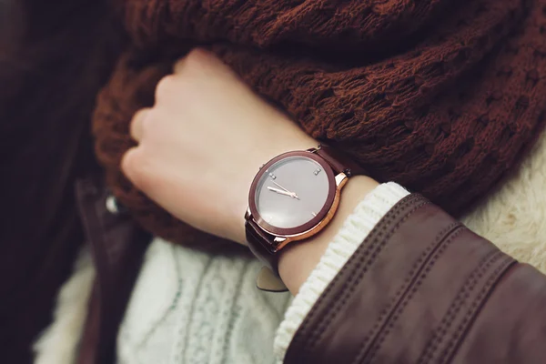 Elegant outfit. Closeup. Brown wrist watch on hand of stylish woman. Fashionable girl at the street. Female fashion.