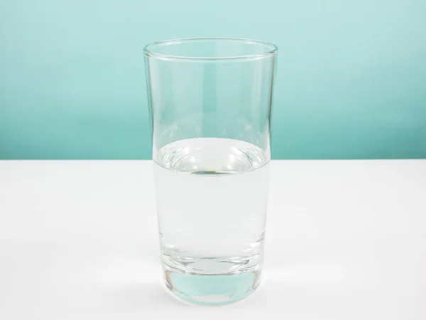 Half empty or half full glass of water on white table