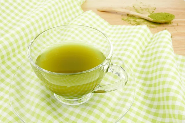 The cup of green tea on green cotton fabric