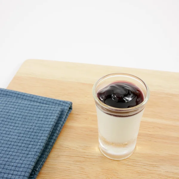 The tasty homemade blueberry panna cotta (Italian pudding dessert) in the small glass and blue cotton fabric