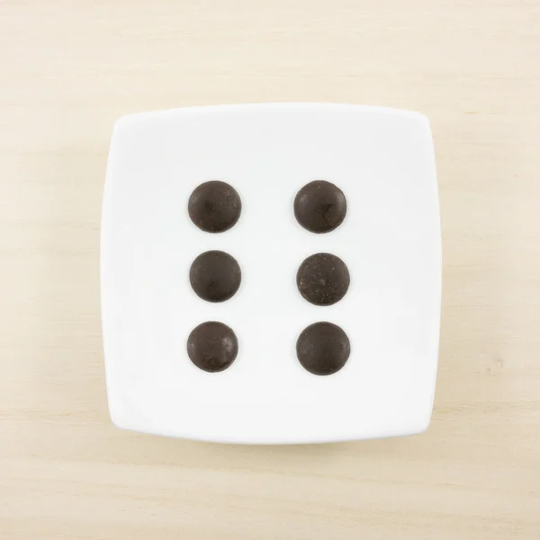 The six dark chocolate buttons and small white square disk