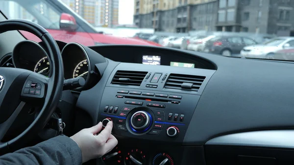 A man adjusts a radio receiver and adjusts the volume in the car