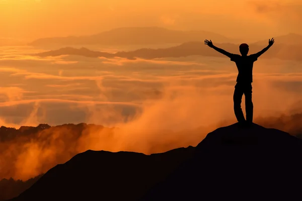 Silhouette of tourist man spread hand on top of a mountain enjoy