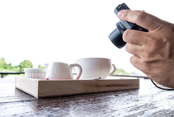 A man taking photo of coffee set.  Handholding camera shooting food shot.