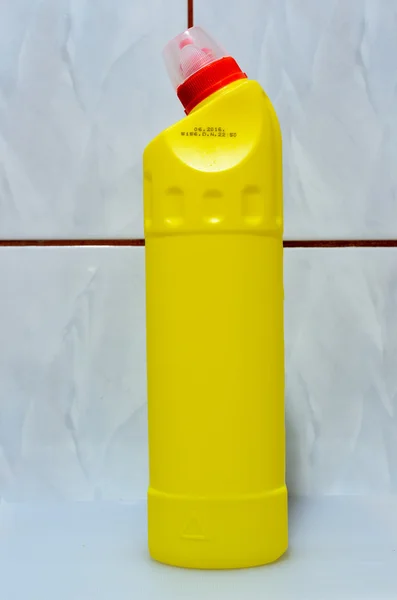 A yellow bottle, full of cleaning fluid over tiles wall