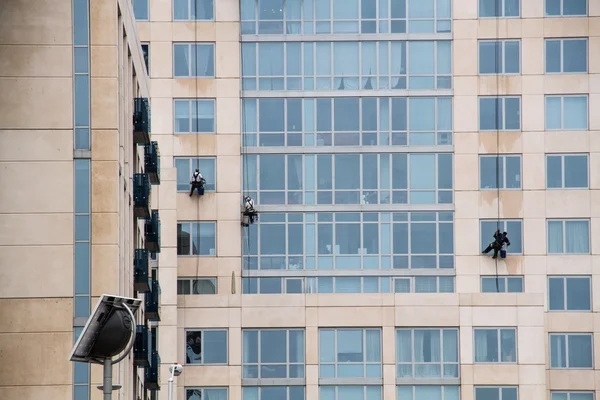Window cleaners clinging to the facade of a residential building.